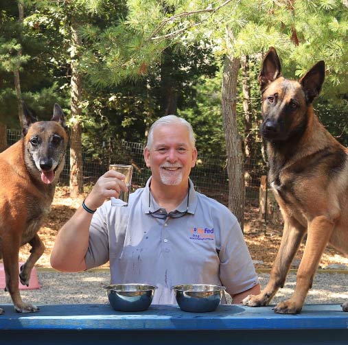 Rick Alto trainer seated with Tia and Ace his Belgian Malinoise on either side next to him